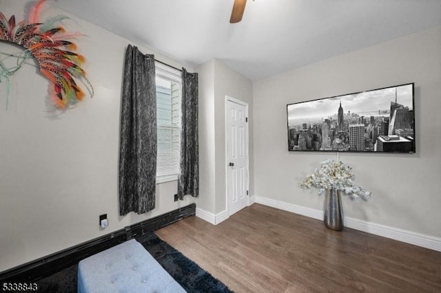 interior space with a baseboard heating unit, a ceiling fan, baseboards, and wood finished floors