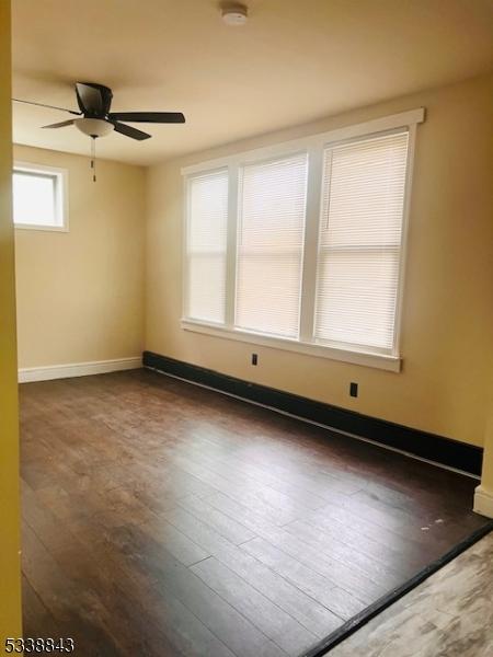 spare room featuring ceiling fan, baseboards, and wood finished floors