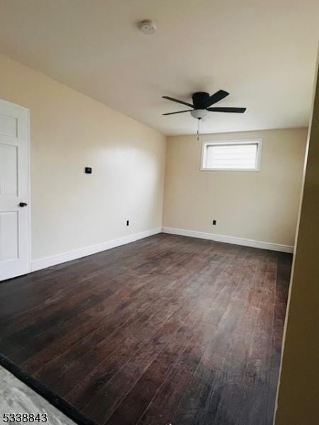 empty room with baseboards, a ceiling fan, and dark wood-style flooring