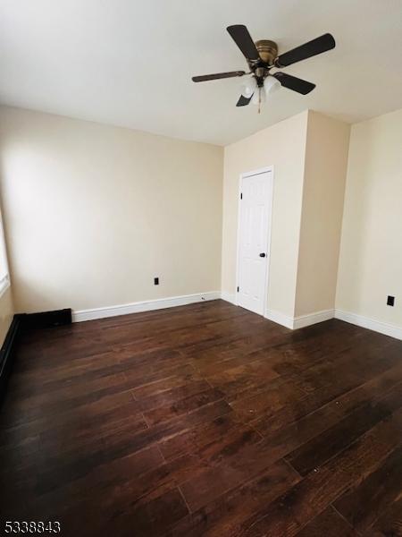 empty room featuring dark wood-style floors, baseboards, and a ceiling fan