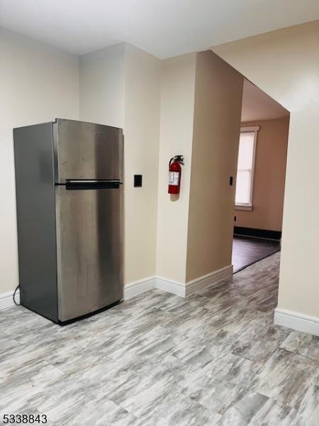 kitchen featuring light wood-style flooring, baseboards, and freestanding refrigerator