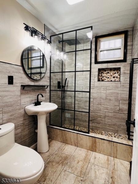 bathroom featuring toilet, a shower stall, and tile walls