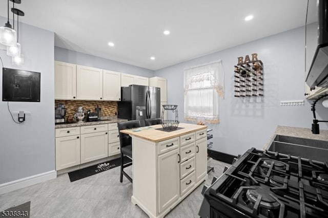 kitchen featuring stainless steel refrigerator with ice dispenser, decorative backsplash, gas stove, wood counters, and electric panel