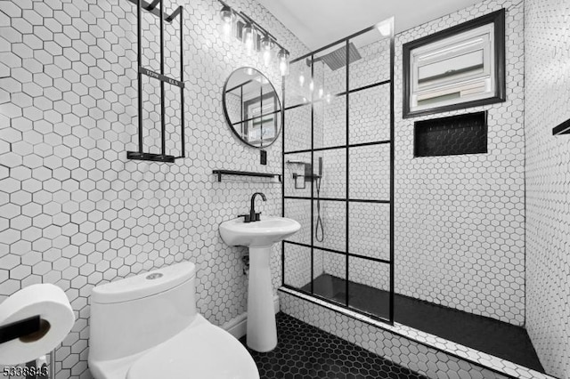 full bath featuring tiled shower, tile patterned floors, toilet, and tile walls