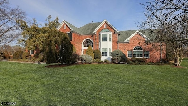 traditional home featuring a front lawn and brick siding