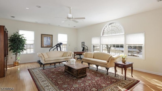 living area with light wood-type flooring, baseboards, and a ceiling fan