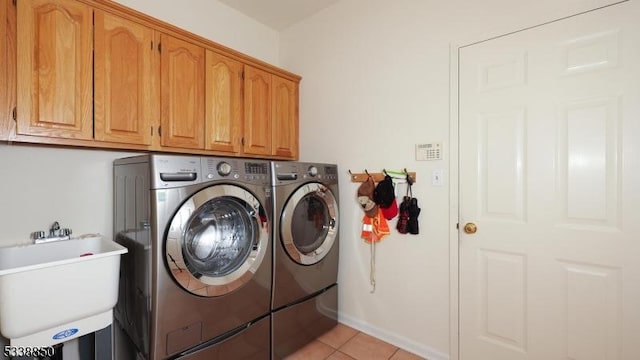 washroom featuring washer and clothes dryer, light tile patterned flooring, a sink, and cabinet space