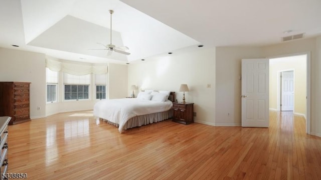 unfurnished bedroom featuring a tray ceiling, visible vents, light wood-style flooring, ceiling fan, and baseboards