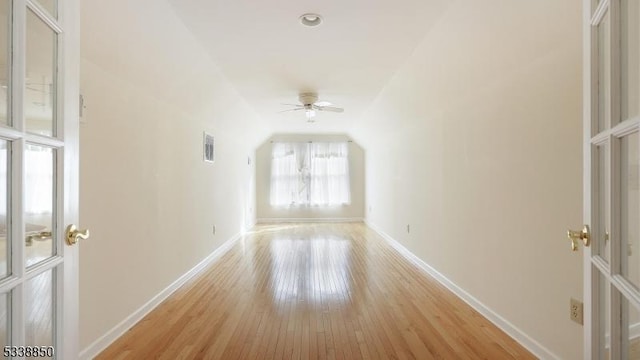 spare room featuring visible vents, baseboards, a ceiling fan, vaulted ceiling, and light wood-style floors