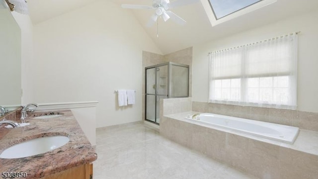 bathroom featuring a ceiling fan, vaulted ceiling with skylight, a sink, and double vanity