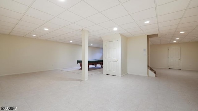 finished basement with a paneled ceiling, baseboards, and recessed lighting