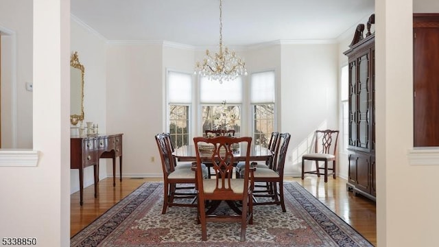 dining area with ornamental molding, wood finished floors, a wealth of natural light, and a notable chandelier