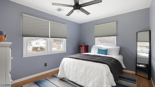 bedroom with ceiling fan, wood finished floors, visible vents, and baseboards