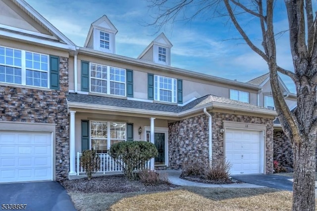 view of property with aphalt driveway, roof with shingles, stucco siding, an attached garage, and stone siding