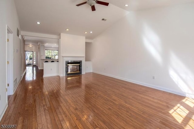 unfurnished living room featuring visible vents, hardwood / wood-style floors, a glass covered fireplace, ceiling fan, and baseboards