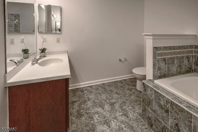 bathroom with baseboards, a garden tub, vanity, and toilet