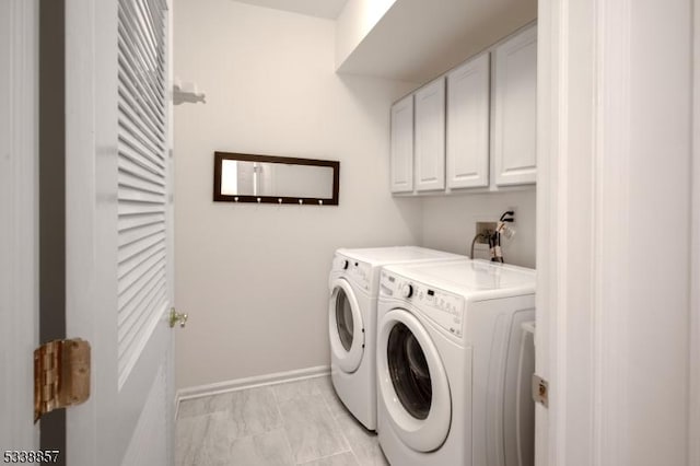 washroom featuring washer and dryer, marble finish floor, cabinet space, and baseboards