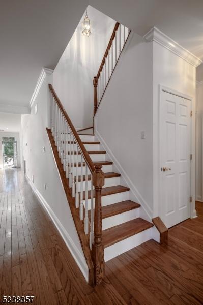 stairway featuring ornamental molding, baseboards, and wood finished floors