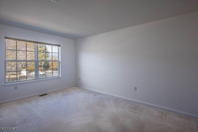 spare room with carpet flooring, visible vents, and baseboards