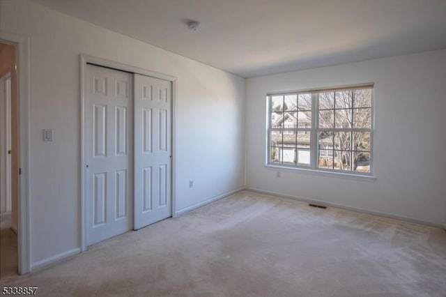 unfurnished bedroom featuring carpet, visible vents, baseboards, and a closet