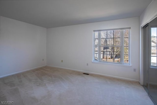 unfurnished room featuring light carpet, visible vents, and baseboards