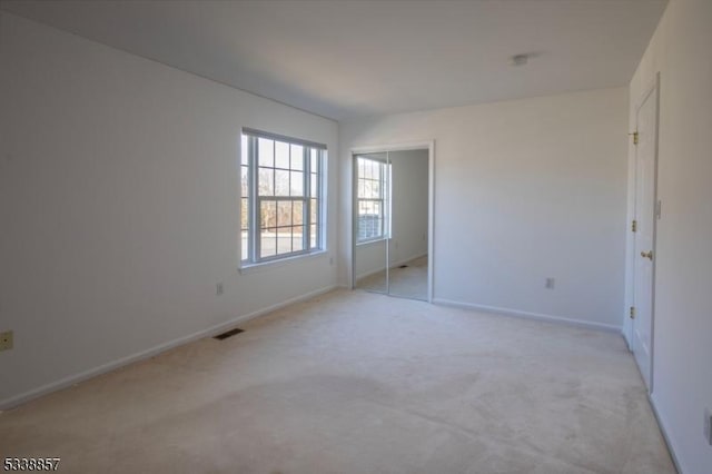 unfurnished bedroom with light colored carpet, a closet, visible vents, and baseboards