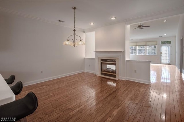 unfurnished living room with ornamental molding, wood-type flooring, a multi sided fireplace, and visible vents