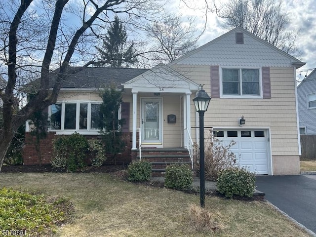 split level home with an attached garage, a front lawn, and aphalt driveway