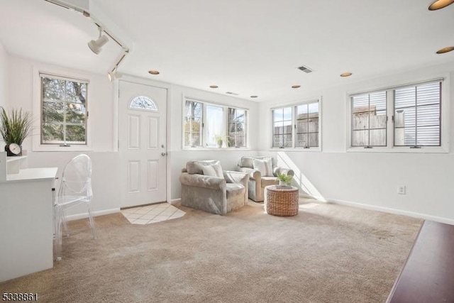 living area featuring carpet, baseboards, visible vents, and rail lighting