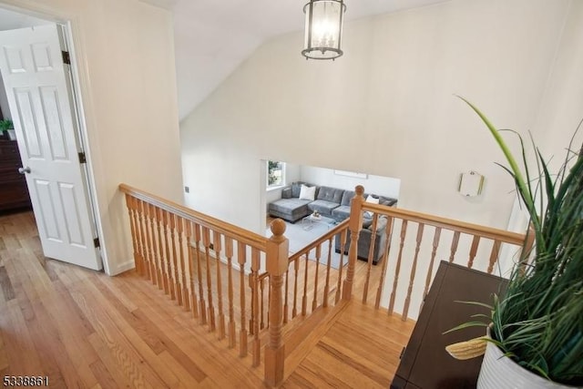 interior space with light wood-type flooring, a chandelier, vaulted ceiling, and an upstairs landing