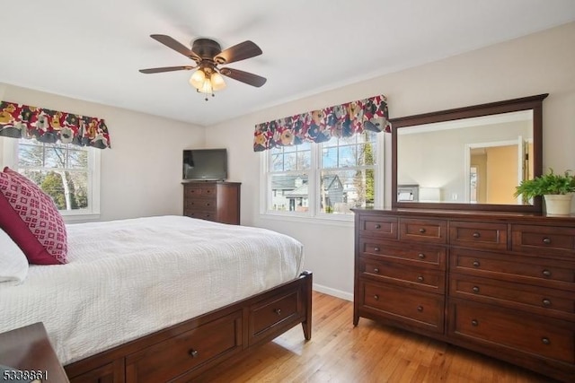 bedroom with light wood-style floors, multiple windows, ceiling fan, and baseboards