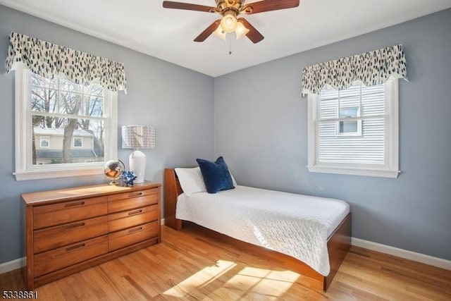 bedroom with light wood-type flooring, ceiling fan, and baseboards