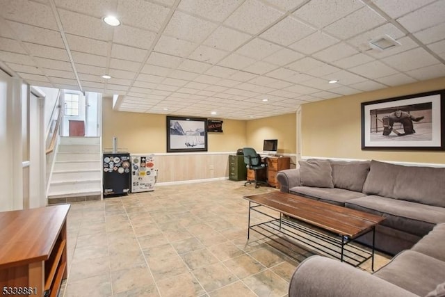 living room with a paneled ceiling, a wainscoted wall, visible vents, and stairway