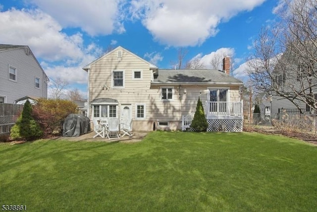 back of property with a patio, a lawn, a chimney, and fence