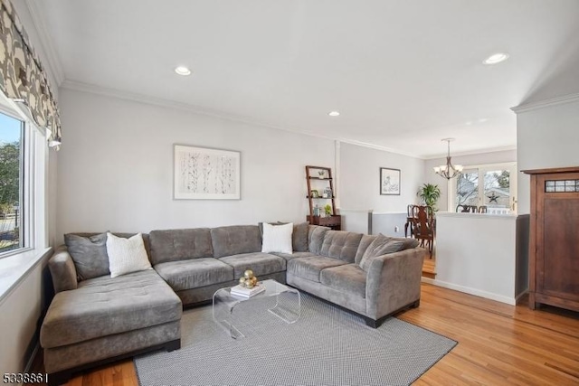 living area with ornamental molding, light wood-style flooring, a wealth of natural light, and a notable chandelier