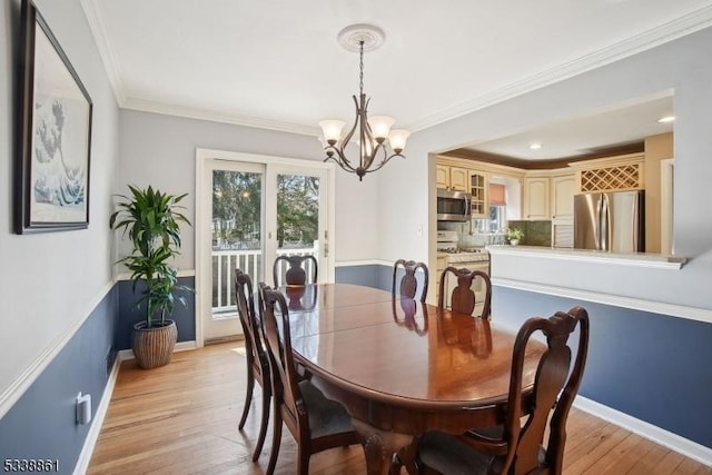 dining space featuring light wood finished floors, ornamental molding, a notable chandelier, and baseboards