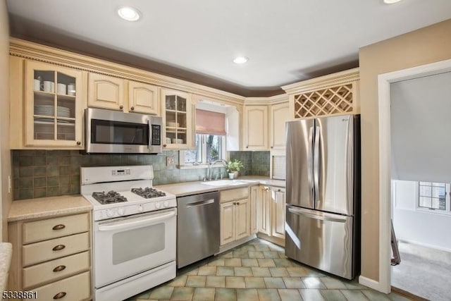 kitchen with stainless steel appliances, light countertops, a sink, and decorative backsplash