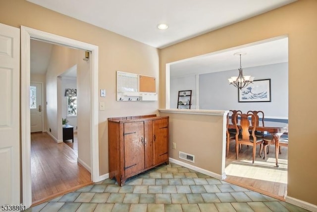 hallway featuring visible vents, baseboards, and an inviting chandelier