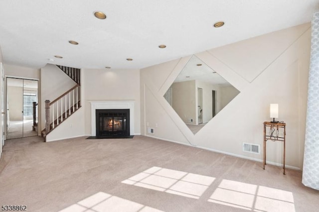 unfurnished living room with a fireplace with flush hearth, light colored carpet, visible vents, and stairway