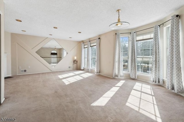 unfurnished room featuring visible vents, light carpet, and a textured ceiling