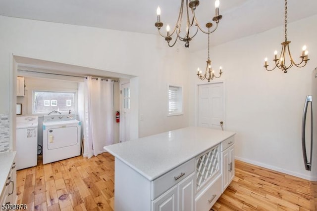 kitchen featuring independent washer and dryer, white cabinetry, pendant lighting, and light hardwood / wood-style floors