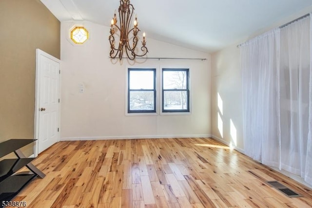 unfurnished dining area featuring lofted ceiling, a notable chandelier, and light hardwood / wood-style flooring