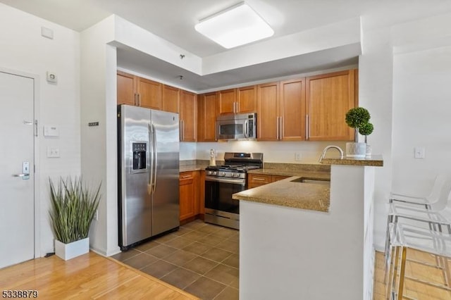 kitchen featuring sink, appliances with stainless steel finishes, light stone counters, and tile patterned floors