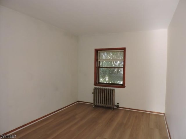 empty room featuring radiator, baseboards, and wood finished floors