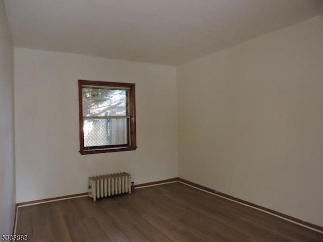 empty room featuring radiator heating unit, baseboards, and wood finished floors