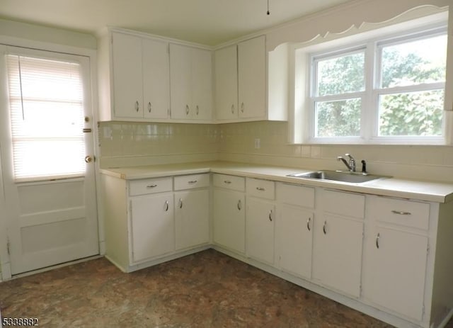 kitchen featuring a wealth of natural light, tasteful backsplash, white cabinets, and a sink