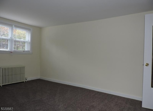 empty room with radiator heating unit, dark carpet, and baseboards