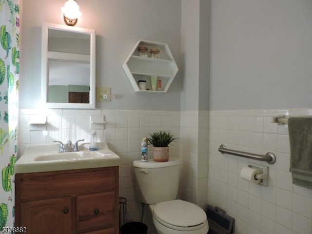 bathroom with wainscoting, vanity, toilet, and tile walls