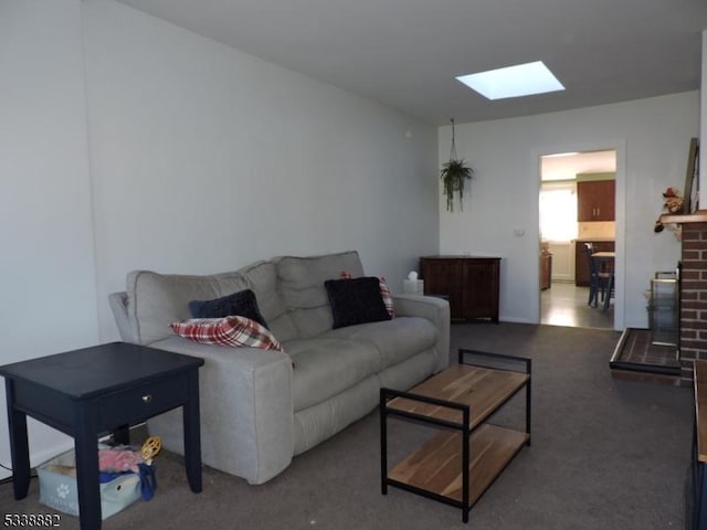 living area featuring a skylight, a brick fireplace, and carpet