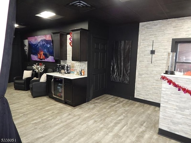 interior space featuring a bar, beverage cooler, and light wood-style flooring